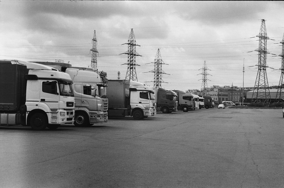 a-black-and-white-photo-of-trucks-parked-in-a-lot-vz3hzlrkpbe