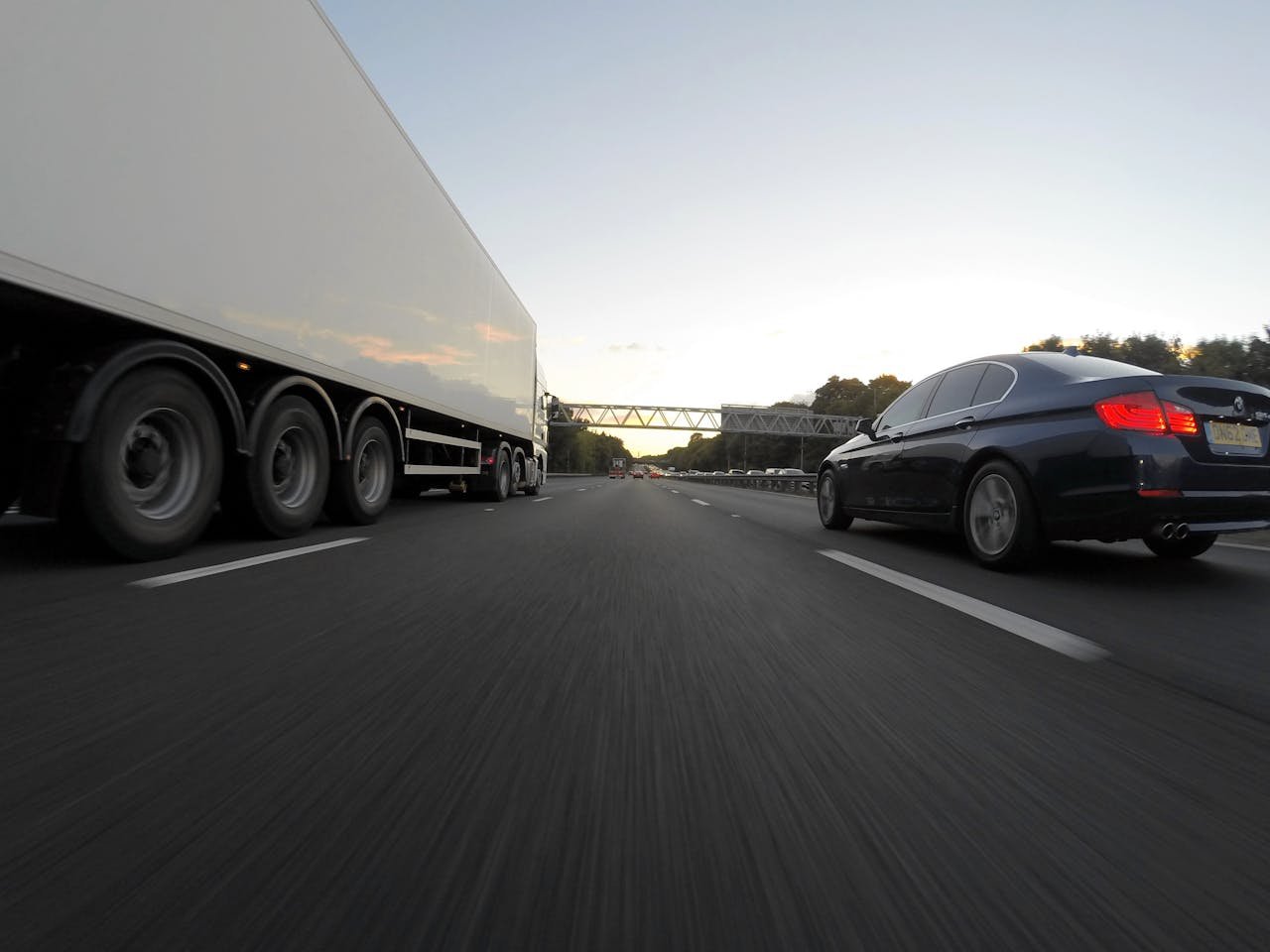 Cars and a truck speed along a highway under the clear sky, showcasing transportation dynamics.
